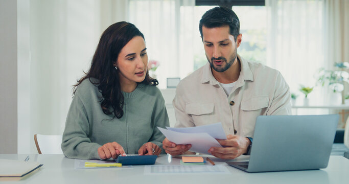 Young Latin couple male, female serious focus on laptop computer check document paper pay bills online plan budget expense in living room at home. Marriage money trouble, Family budget plan concept.