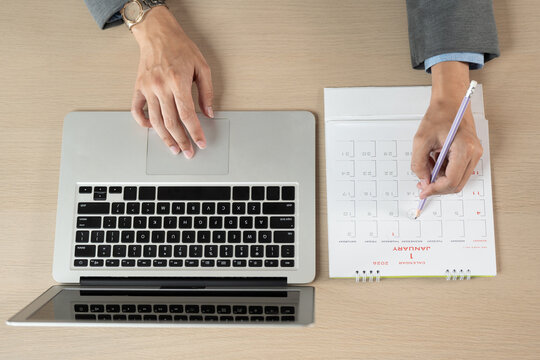 Time management concept, business professional plans work schedule on desk calendar beside laptop in office, productivity, planning, calendar, schedule, deadline