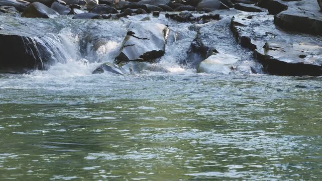 Mountain River with Small Waterfall Flowing Over Smooth River Rocks 