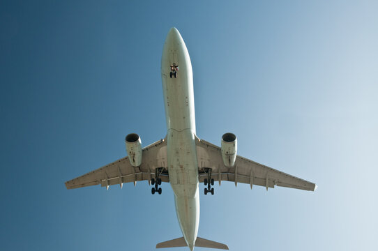 View of a commercial airliner flying overhead with landing gear deployed against a clear blue sky in Richmond, British Columbia, Canada.