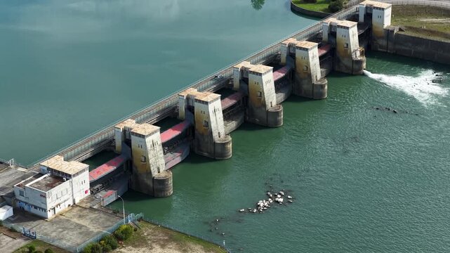 Hydroelectric river dam managing water flow and generating renewable energy, showing massive concrete floodgates with white van driving across bridge superstructure