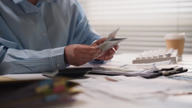 Asian woman using letter opener tool to open white envelope mail document while working at office workstation desk.