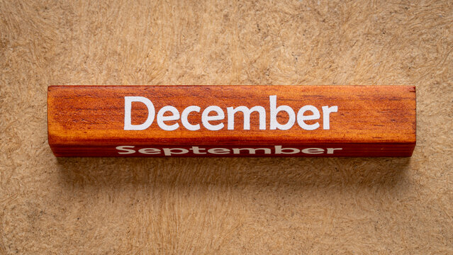 December text on wooden block against handmade bark paper in earth tones, calendar concept