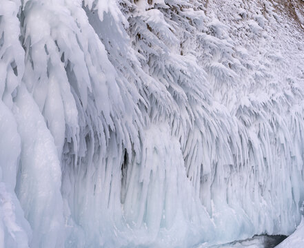View of intricate ice formations and icicles clinging to the rocky cliffs of Lake Baikal, Russia.