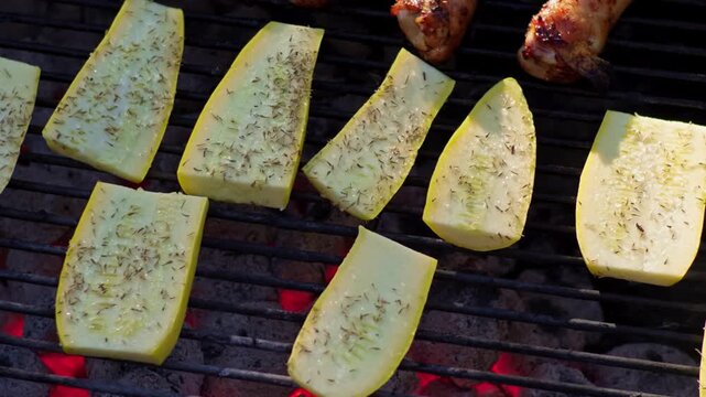 Seasoned yellow squash slices grill over hot glowing charcoal embers