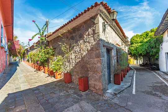 View of a historic stone building with a terracotta roof and potted plants along a cobblestone street in Honda, Tolima, Colombia.