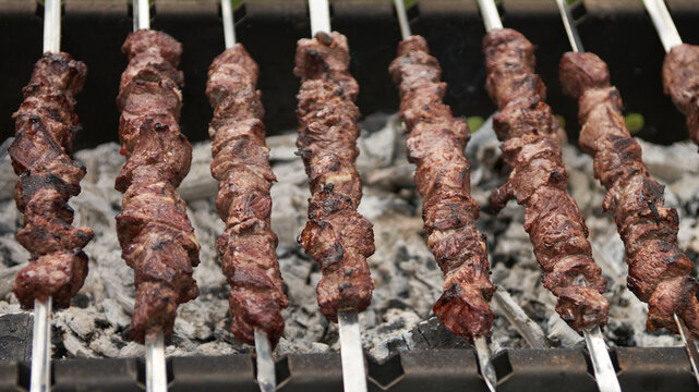 Chunks of succulent meat, threaded onto skewers, finish cooking over smoldering coals.
