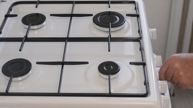 A Man in the Kitchen Stops the Gas Cooker using the Front Button and Closing the Fire. A Person Closing the Fire from the Cooker.