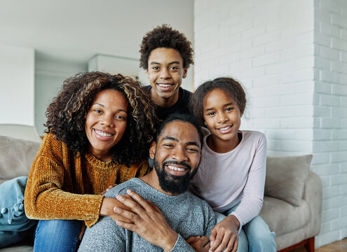 Portrait of a happy black family mother father and kids at home on couch