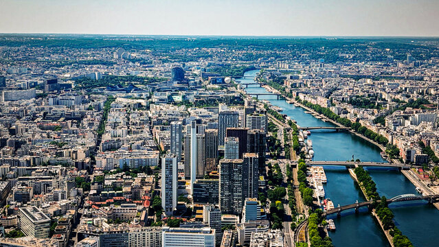 View of the Seine river flowing through the dense urban landscape with modern skyscrapers and historic buildings in Paris, Ile-de-France, France.