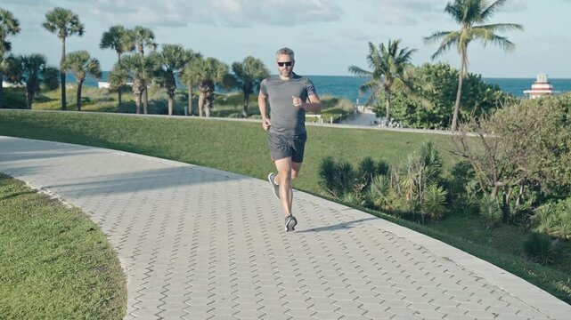 Fitness and sport. Man running with energy. Sport lifestyle. Sportsman running with fitness mat. Sport man training outdoor in city park. Healthy lifestyle with daily fitness