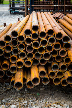 Stack of rusty round steel pipe ends in an outdoor storage yard