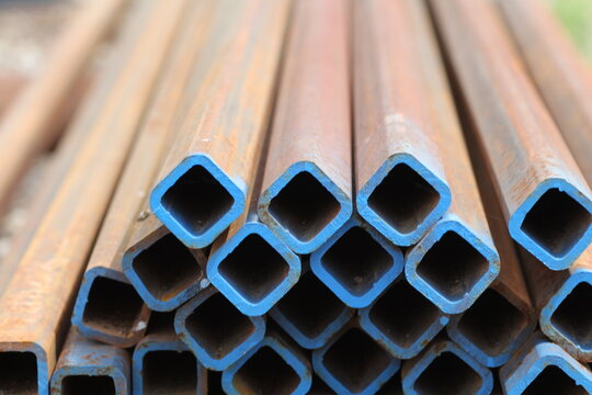 Stacked square steel tubes with blue painted ends in close up