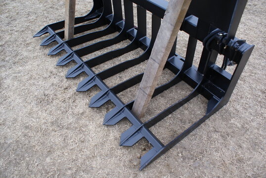 Black steel grapple tines resting on dry grass in close view