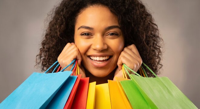 Happy young woman holding colorful shopping bags while smiling cheerfully during seasonal retail sale discount shopping spree and celebration