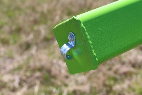 Square green steel tube end with a bolted clamp over grass