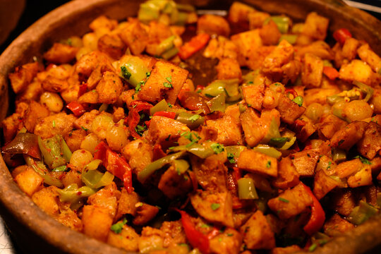 Traditional baked meat stew with potatoes and bell peppers in rustic clay pot close up. Hot savory vegetable goulash with oriental spices at dinner buffet. National culinary food concept, hotel restau