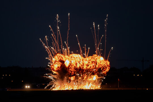 View of a pyrotechnic explosion with bright orange flames and sparks shooting into the dark sky at Bucharest Henri Coanda International Airport, Otopeni, Judetul Ilfov, Romania.