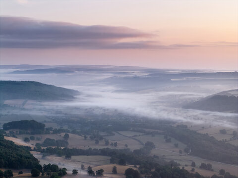 Beautiful drone landscape image over Stanton Moor in Summer Heather sunrise