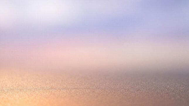 Soft pastel abstract background with a textured foreground surface and a blurry gradient sky in warm golden, pink, and lavender hues