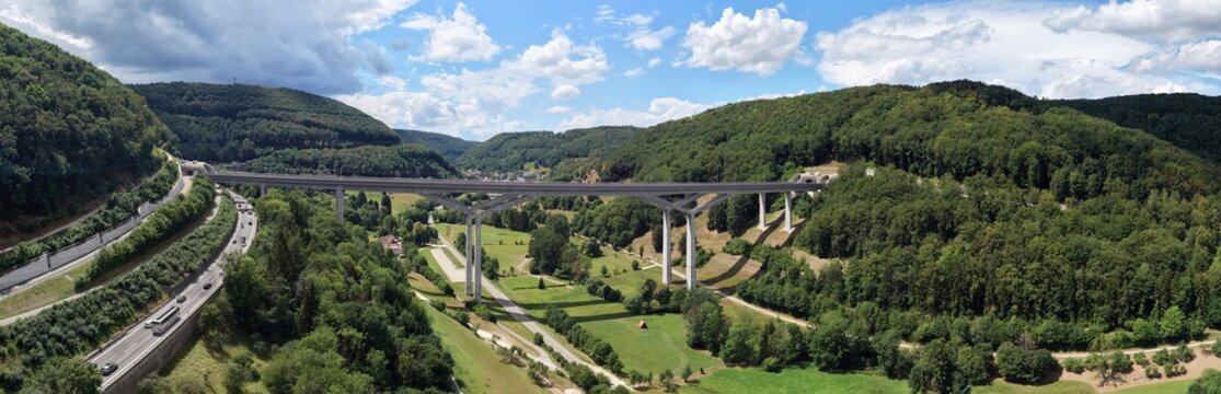 Aerial view of the Filstalbrucke, a high-speed railway bridge spanning the valley with lush green hills and a nearby highway in Muhlhausen im Tale, Baden-Wurttemberg, Germany.