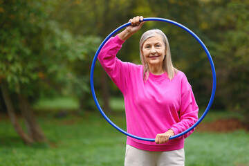 Senior woman with hula hoop in park, space for text © New Africa