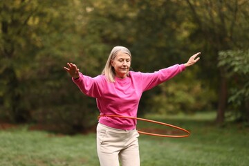 Senior woman exercising with hula hoop outdoors © New Africa