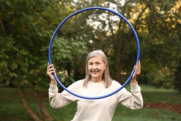 Senior woman with hula hoop in park © New Africa
