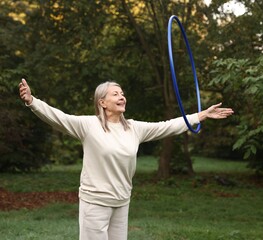 Senior woman exercising with hula hoop outdoors © New Africa