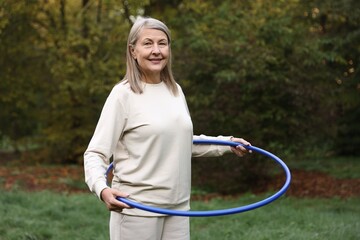 Senior woman exercising with hula hoop outdoors © New Africa