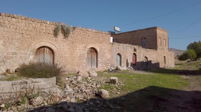 Dereici or Killit, Syriac village near Savur, Mardin, Turkey: old stone house with arched wooden doors and rubble in front