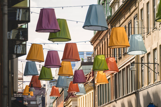 Colorful hanging lampshades decorate a narrow European city street.