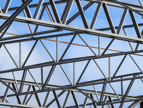 Steel roof trusses forming geometric industrial construction framework.