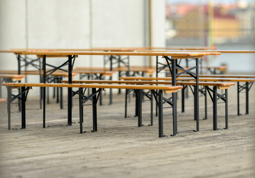 Rows of empty wooden tables and benches await outdoor gathering.