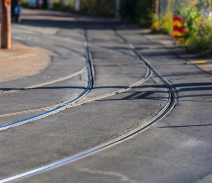 Curving tram rails embedded in asphalt urban roadway.
