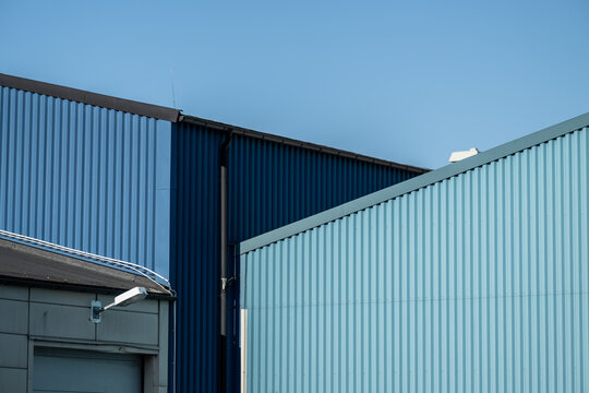 Modern industrial warehouse buildings with blue corrugated metal facade and clear sky.