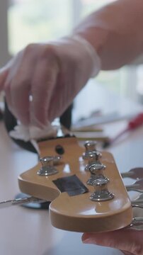 Male luthier performing stepwise electric guitar setup and stringing over workshop workbench