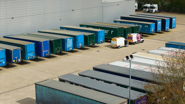 Aerial view of a logistics distribution center with rows of parked semi-trailers and delivery vans in Magna Park, England, United Kingdom.