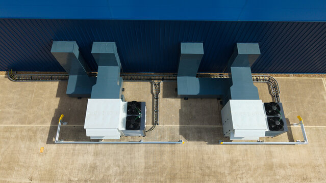 Aerial view of industrial ventilation cooling fans installed on a concrete surface next to a blue metal wall in Lutterworth, England, United Kingdom.