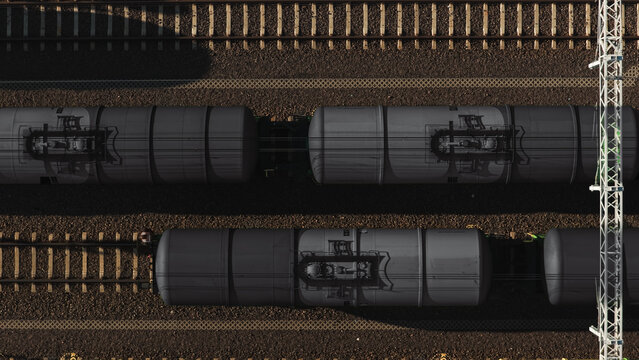Aerial view of oil tank cars on parallel railway tracks with overhead power lines and gravel ballast Germany.