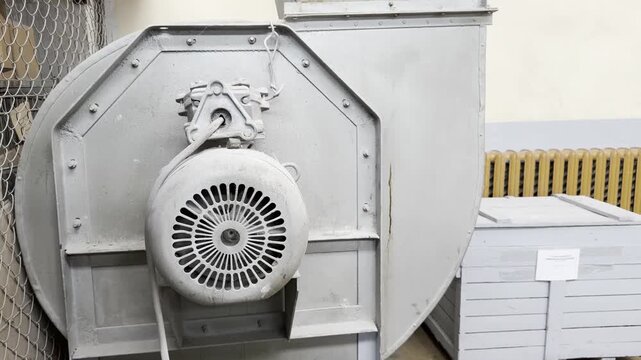 A large industrial blower with a dusty electric motor and metal housing illustrates ventilation equipment, mechanical engineering and factory infrastructure