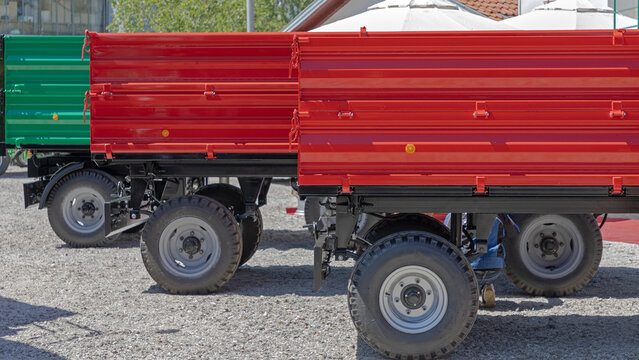 Red Agricultural Dump Trailers for Tractor Transport at Farm Sunny Day
