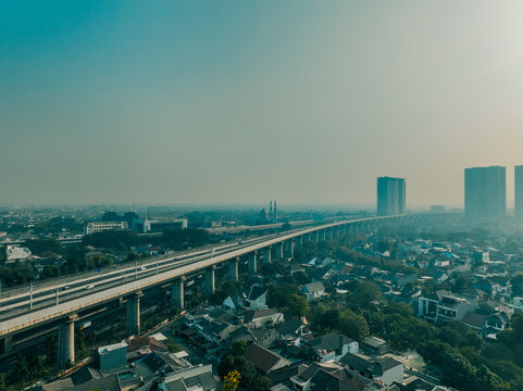 Aerial view of the elevated high-speed railway track cutting through the dense residential rooftops and urban landscape of Bekasi Barat, West Java, Indonesia.