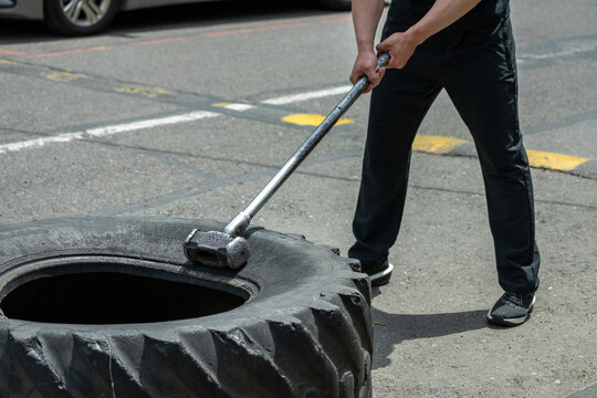 A man performing an exercise with a sledgehammer and a tire.