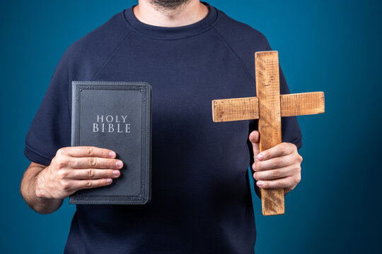 A person holds the Holy Scripture and the Cross in their hands.
