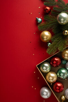 Merry Christmas and Happy New Year with festive ornaments and fir branches on vertical red background with empty space