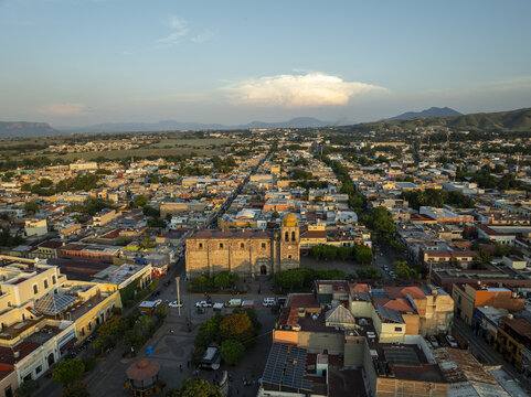Aerial view of the historic Parroquia Santiago Apostol church in the town square, surrounded by traditional colonial architecture, rooftops, and lush trees in Tequila, Jalisco, Mexico.
