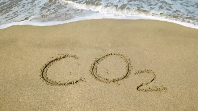 Co2 inscription on sandy beach. Conceptual video showing the chemical formula for carbon dioxide, co2, written on the wet sand of a beach being erased by an incoming ocean wave