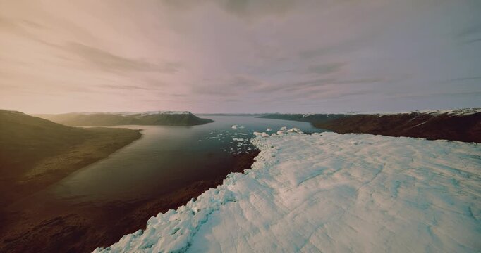 aerial drone survey over melting coast capturing fractured ice and dark water, scientific monitoring perspective with wide horizon and layered clouds, clinical