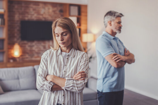 Worried Expression On Face. White Woman And Man In Their 30s Stressed And Having Conflict With Arms Crossed In Living Room. Emotional Strain In Relationship. Family Concept.